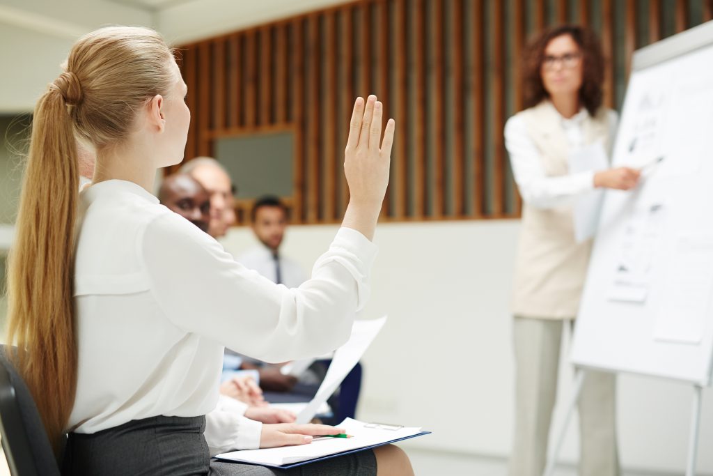 Woman raising her hand to ask a question in a training session.