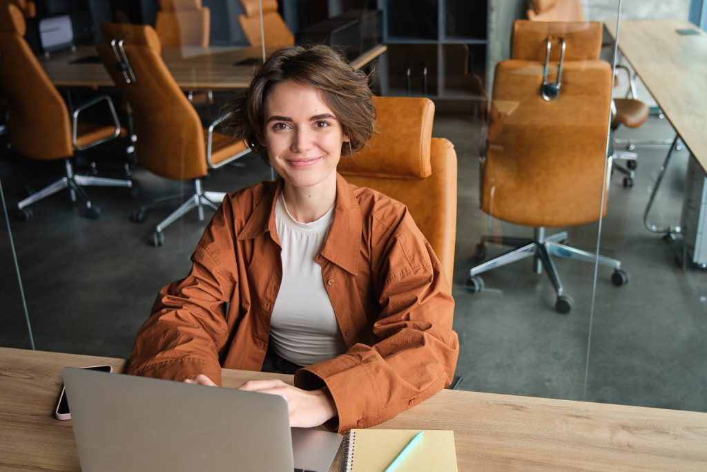 Young professional working on a laptop at a desk in a creative workspace.