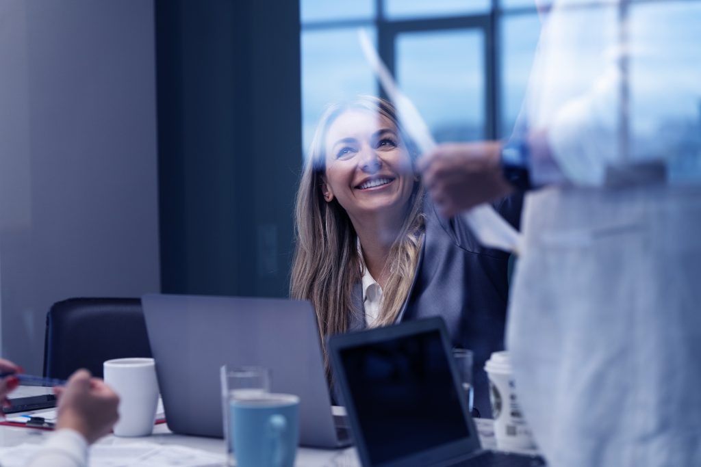 Smiling coworkers collaborating around a laptop during a casual meeting.