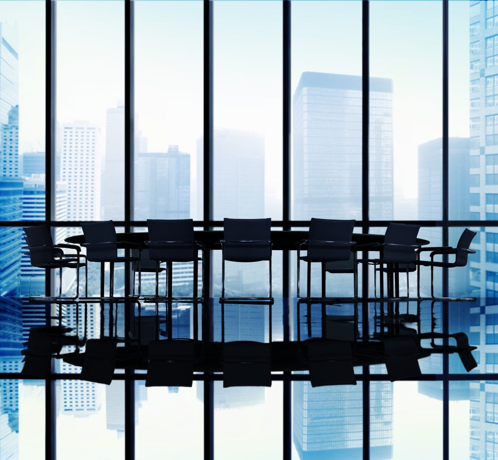 Chairs and tables silhouetted against large windows with city views.