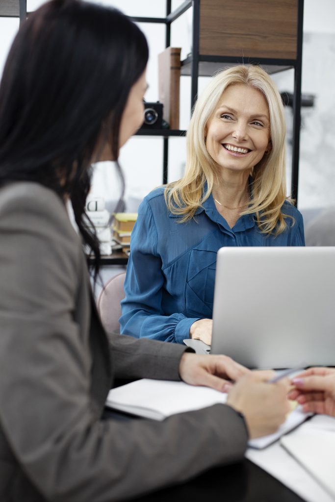Professional meeting with two women talking across a laptop.
