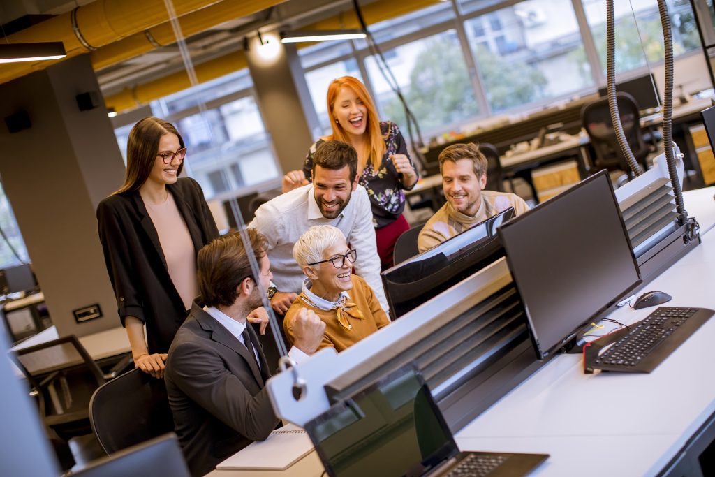 Team of coworkers collaborating around computers in an open office.