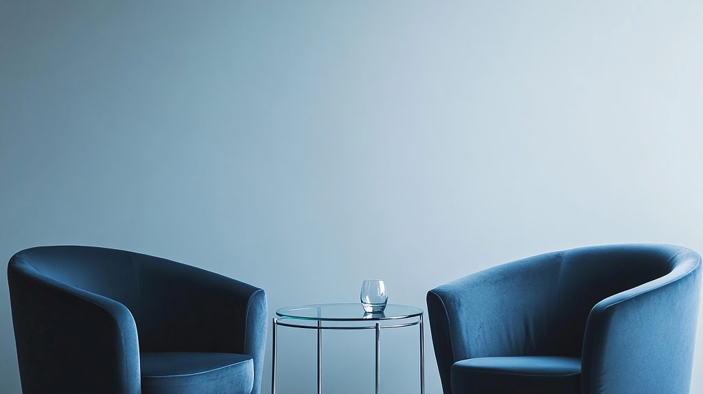 Minimalist meeting area with two chairs and a small table against a plain wall.